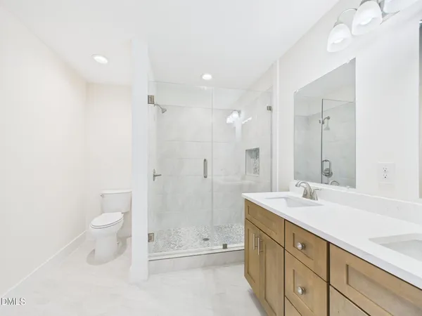 a bathroom with a double vanity sink toilet and shower