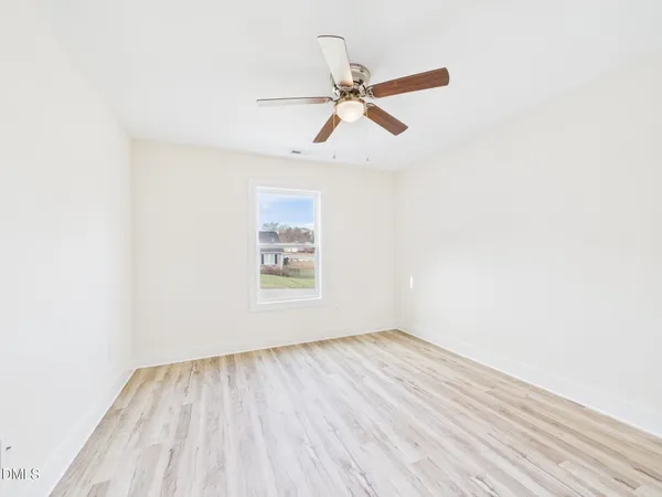an empty room with wooden floor closet and fan