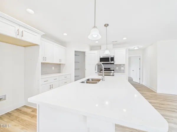 a room with kitchen island a sink stainless steel appliances and cabinets
