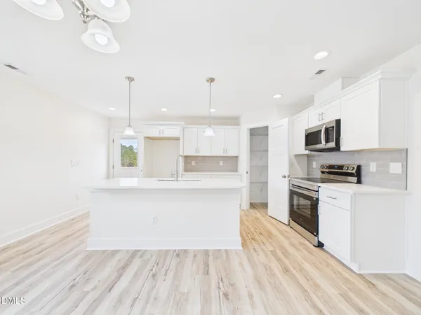 a large kitchen with cabinets wooden floor and stainless steel appliances