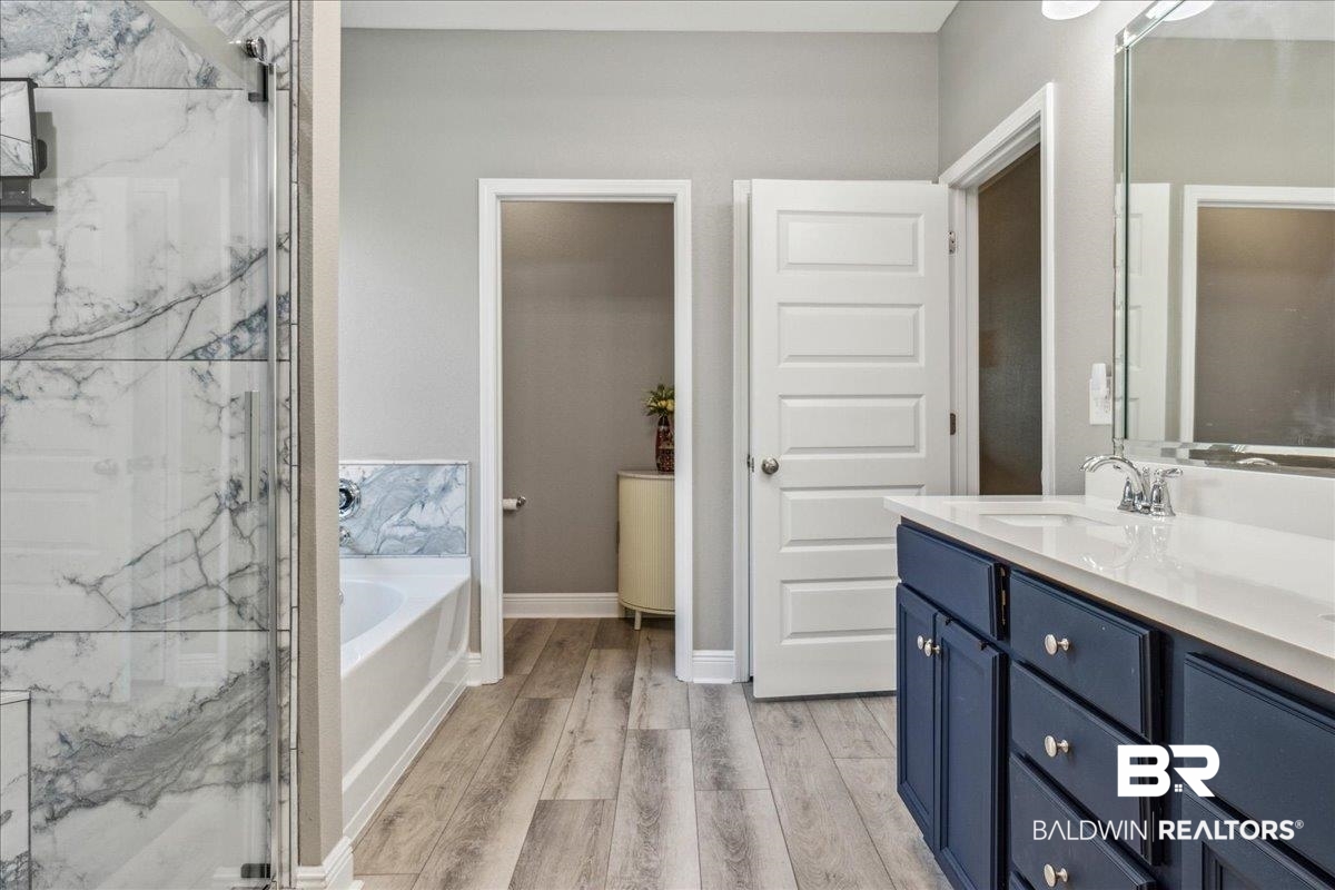 7022 Rocky Rd Loop Gulf Shores, AL 36542 - Photo 24 of 59 Primary Bathroom with vanity, a bath, wood finished floors, and a marble finish shower
