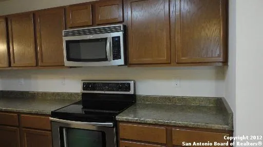 a kitchen with granite countertop stainless steel appliances stove top oven and cabinets