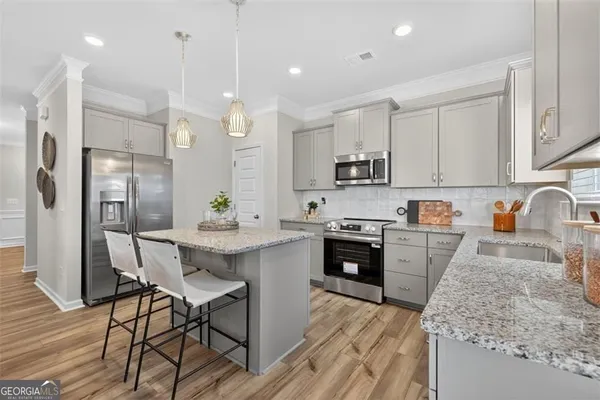 a kitchen with kitchen island granite countertop a sink a stove a refrigerator and island with wooden floor