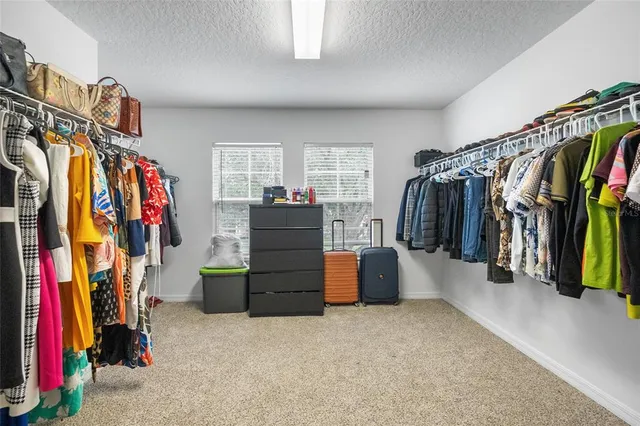 a walk in closet with clothes and shoes