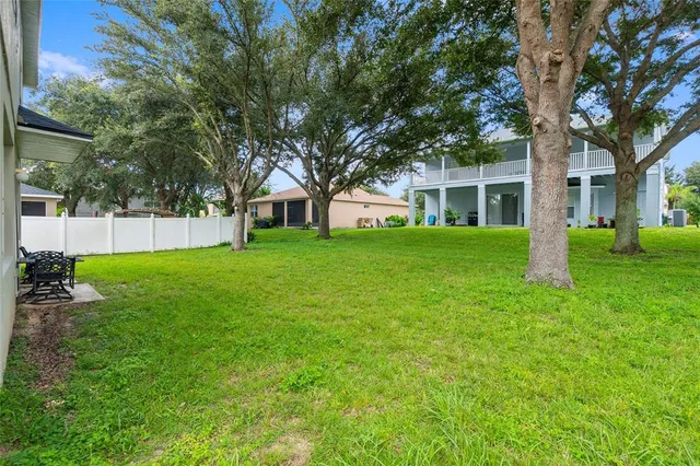 a view of a house with a big yard and large trees