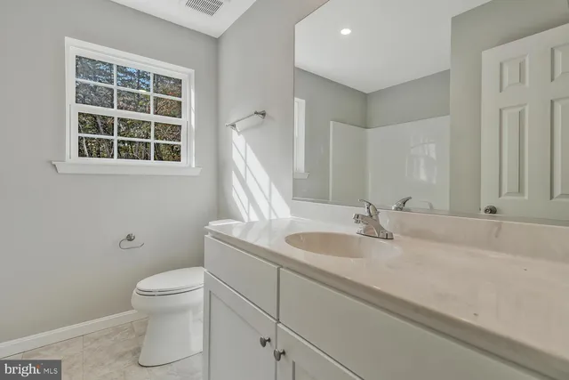 a bathroom with a granite countertop sink toilet and a mirror