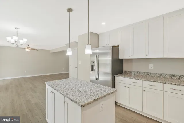 a kitchen with stainless steel appliances granite countertop a sink a refrigerator and white cabinets