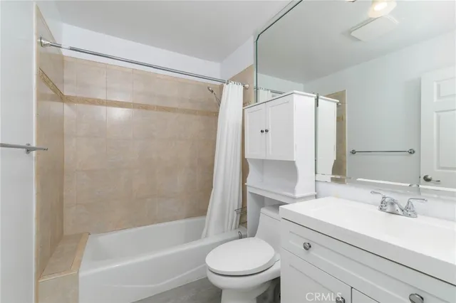 a bathroom with a granite countertop bathtub shower sink vanity and toilet