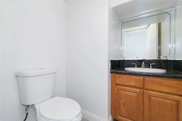 a bathroom with a granite countertop toilet sink and mirror