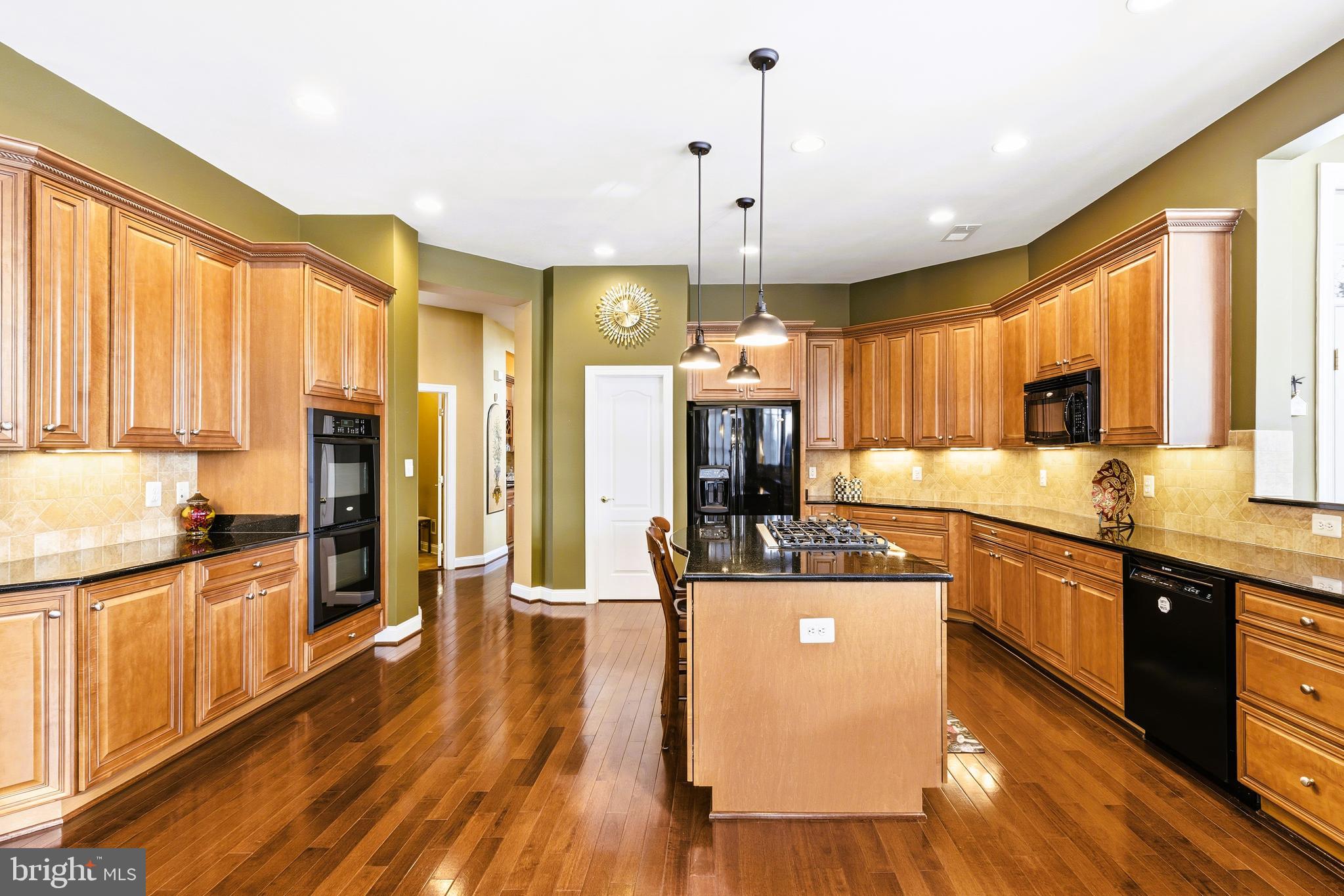19606 Bellingham Lane Leesburg, VA 20175 - Photo 18 of 73 a kitchen with stainless steel appliances kitchen island granite countertop a stove a refrigerator a kitchen island and chairs with wooden floor
