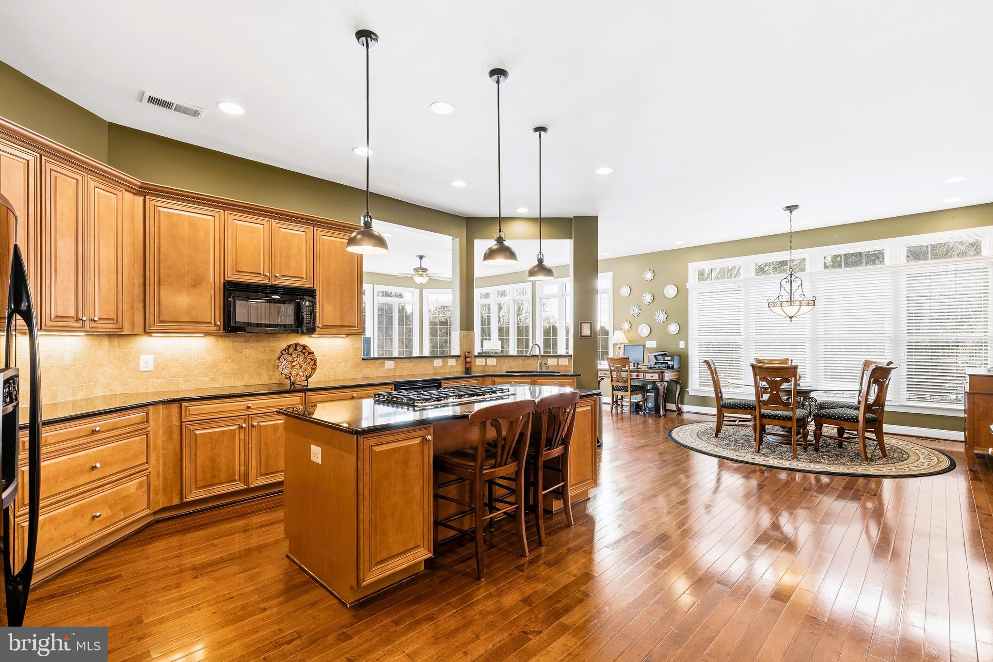19606 Bellingham Lane Leesburg, VA 20175 - Photo 21 of 73 a kitchen with stainless steel appliances granite countertop a stove top oven a dining table and chairs with wooden floor