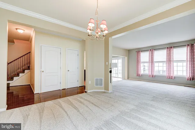 a view of an empty room with window and chandelier fan