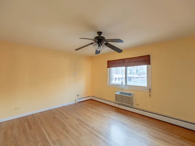 a view of empty room with wooden floor and fan