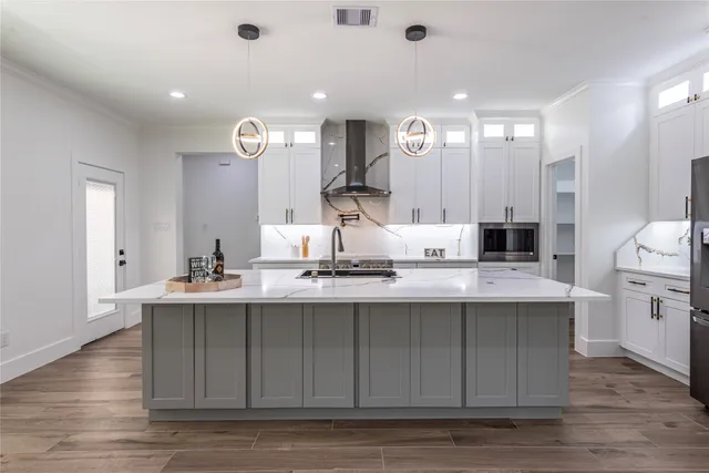 a view of a kitchen with kitchen island a sink wooden floor and stainless steel appliances