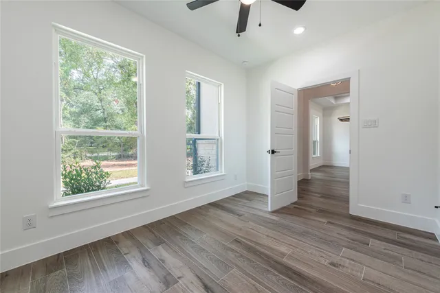 an empty room with wooden floor and windows