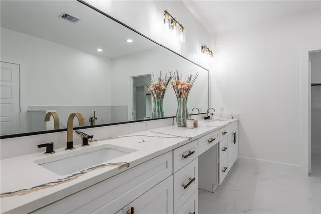 a bathroom with double vanity and a mirror