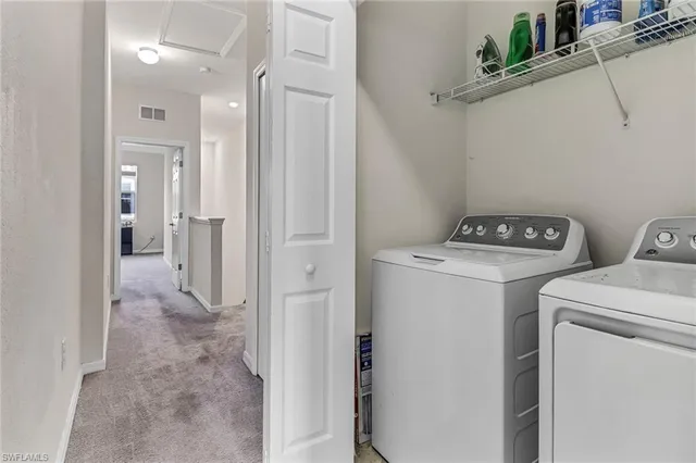 a view of washer and dryer with bathroom in the background