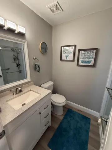 a bathroom with a granite countertop toilet sink and mirror