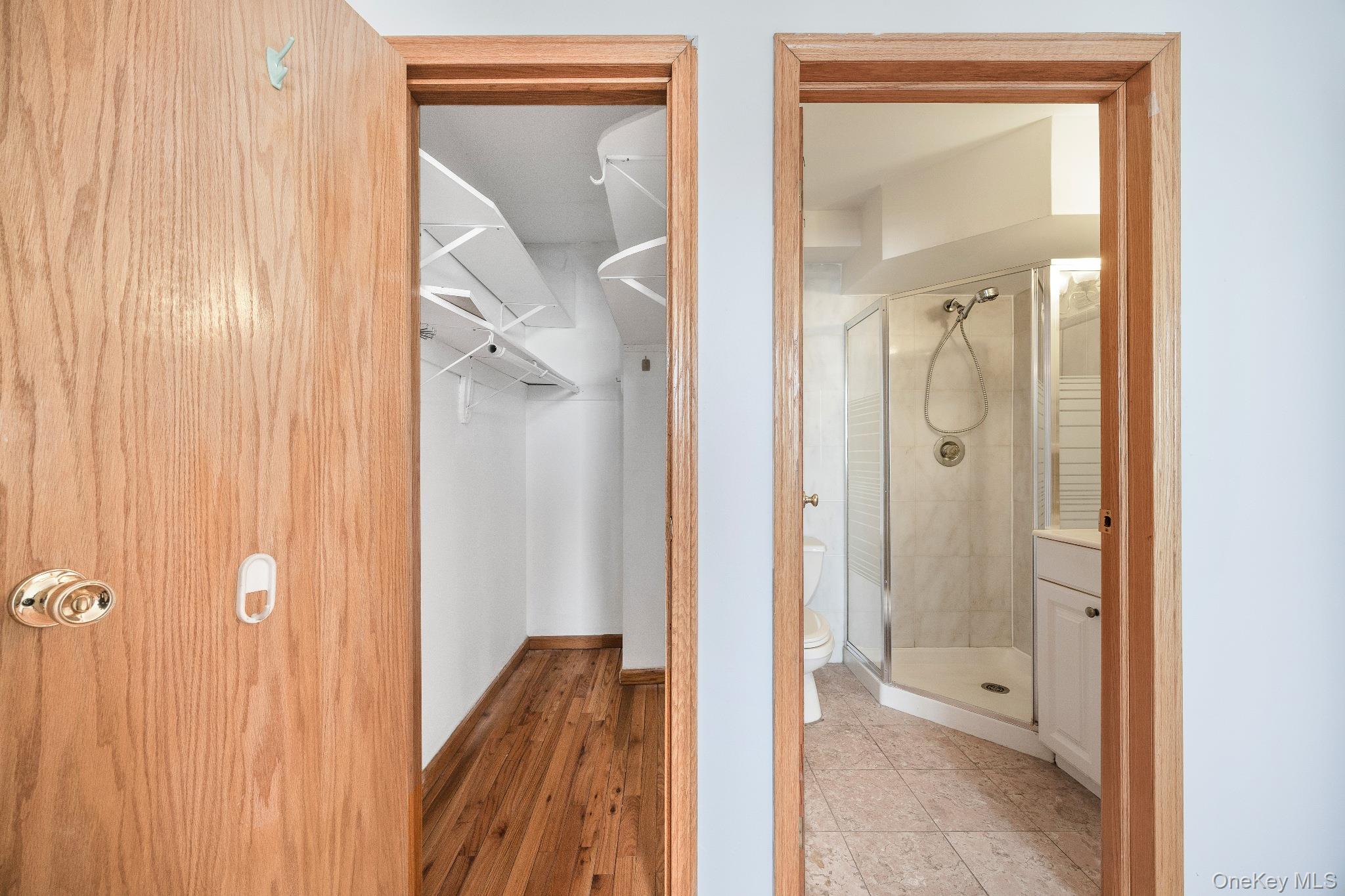 133-36 41st Road, Unit 8F Queens, NY 11355 - Photo 14 of 18 Walk-In Closet / En-Suite Access – The spacious walk-in closet offers built-in shelving and hanging space for organized storage. Conveniently located adjacent to the bathroom, it provides a practical and efficient layout for daily living.