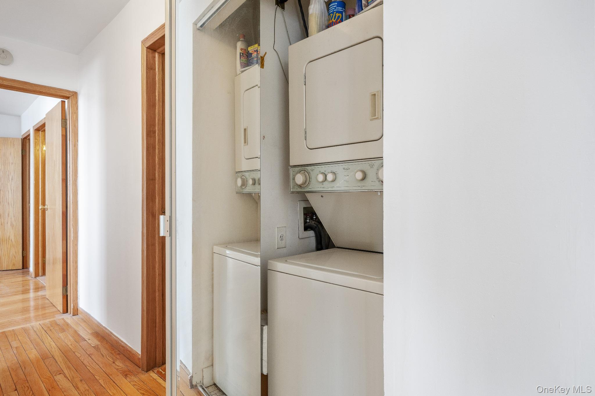 133-36 41st Road, Unit 8F Queens, NY 11355 - Photo 15 of 18 In-Unit Laundry – Convenient in-unit laundry closet with stacked washer and dryer, neatly tucked behind sliding doors. This practical feature adds everyday ease and functionality to the home.