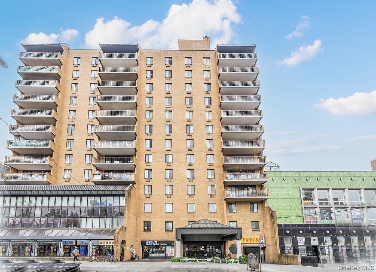 133-36 41st Road, Unit 8F Queens, NY 11355 - Photo 2 of 18 Building Exterior –This well-maintained mid-rise condominium features a classic brick façade with private balconies and a welcoming covered entrance. Located along a vibrant street with nearby shops and services, it offers convenient access to neighborhood amenities and public transportation.