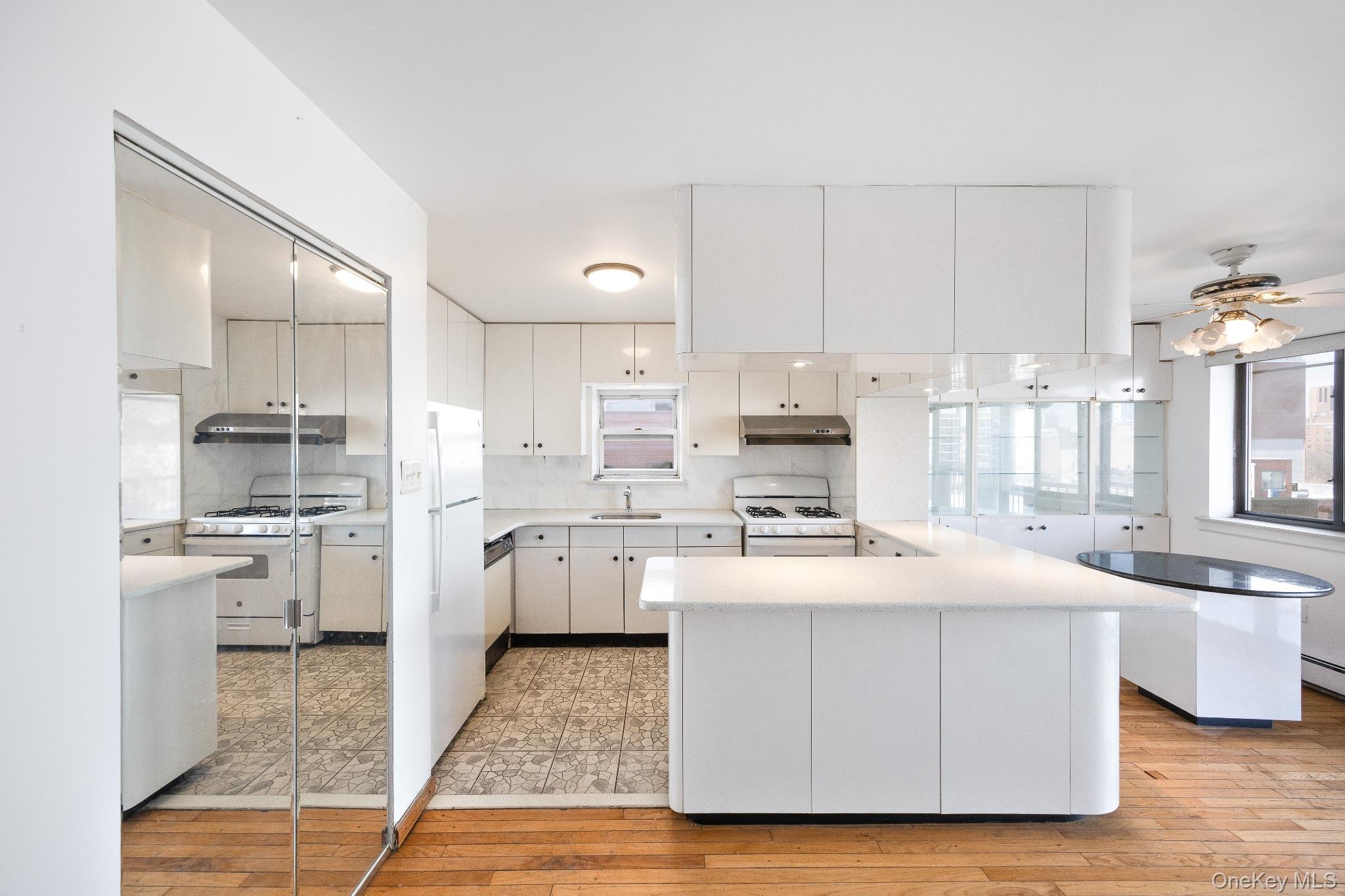 133-36 41st Road, Unit 8F Queens, NY 11355 - Photo 8 of 18 Kitchen – The spacious kitchen features abundant cabinetry, generous counter space, and a convenient peninsula with breakfast bar seating. A practical layout with a window over the sink provides natural light and an efficient space for cooking and meal preparation.