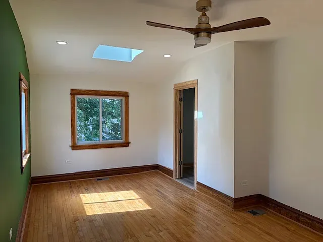 an empty room with wooden floor closet and windows