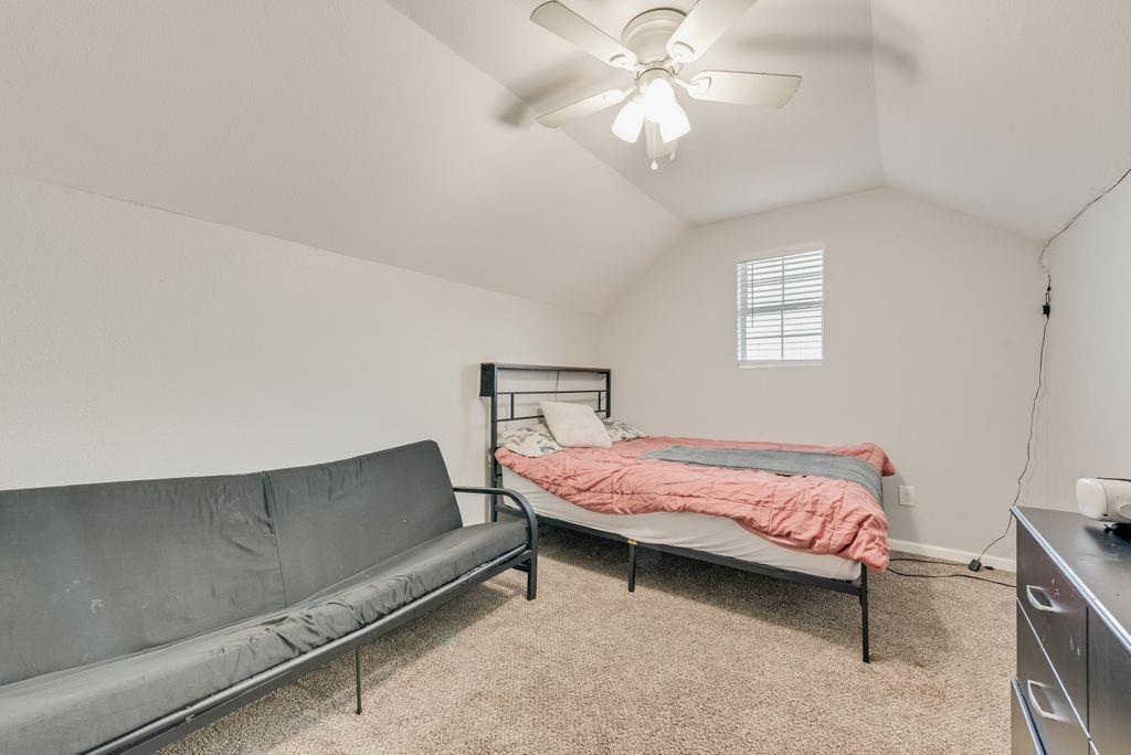 610 Ewing Road Ferris, TX 75125 - Photo 19 of 22 Vaulted ceiling with a ceiling fan, carpeted flooring, and a window with blinds