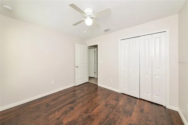 an empty room with wooden floor and a ceiling fan