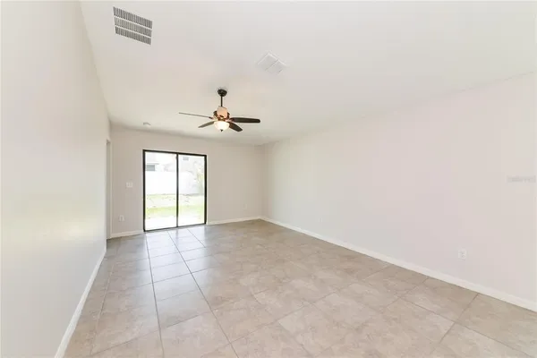 an empty room with chandelier fan and windows