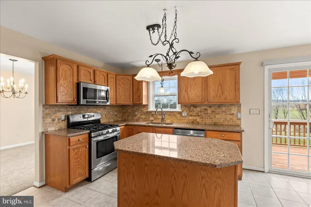 a kitchen with stainless steel appliances granite countertop a sink a stove top oven a counter space and cabinets