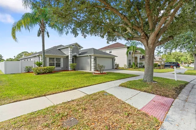 a front view of a house with a yard and palm trees