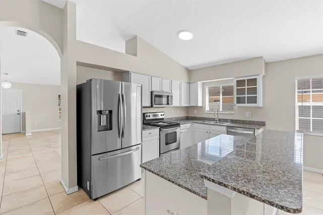 a kitchen with stainless steel appliances granite countertop a refrigerator a stove a sink and a microwave