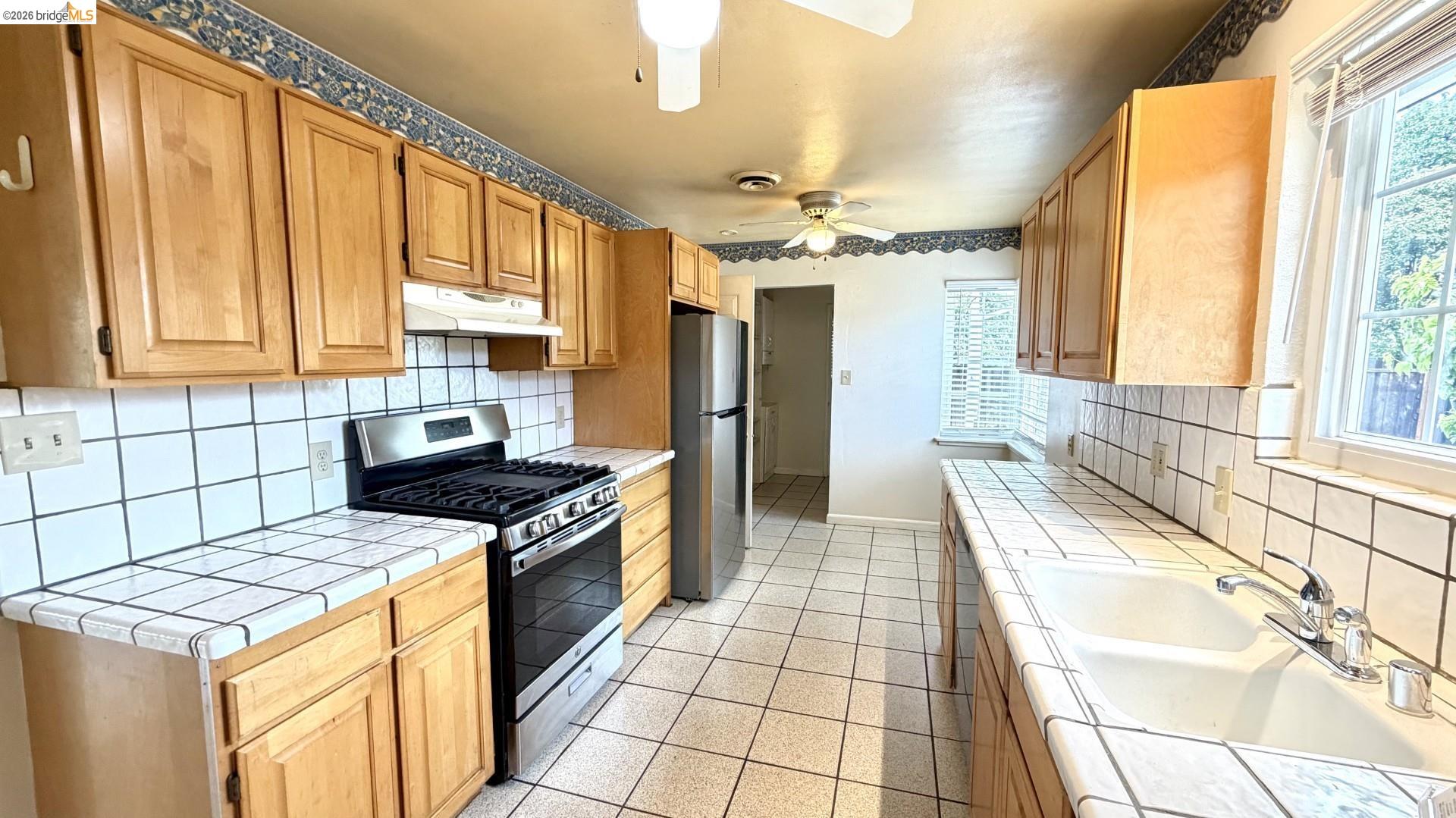 3407 Cowell Road Concord, CA 94518 - Photo 11 of 24 Kitchen featuring stainless steel appliances, backsplash, tile counters, and a ceiling fan