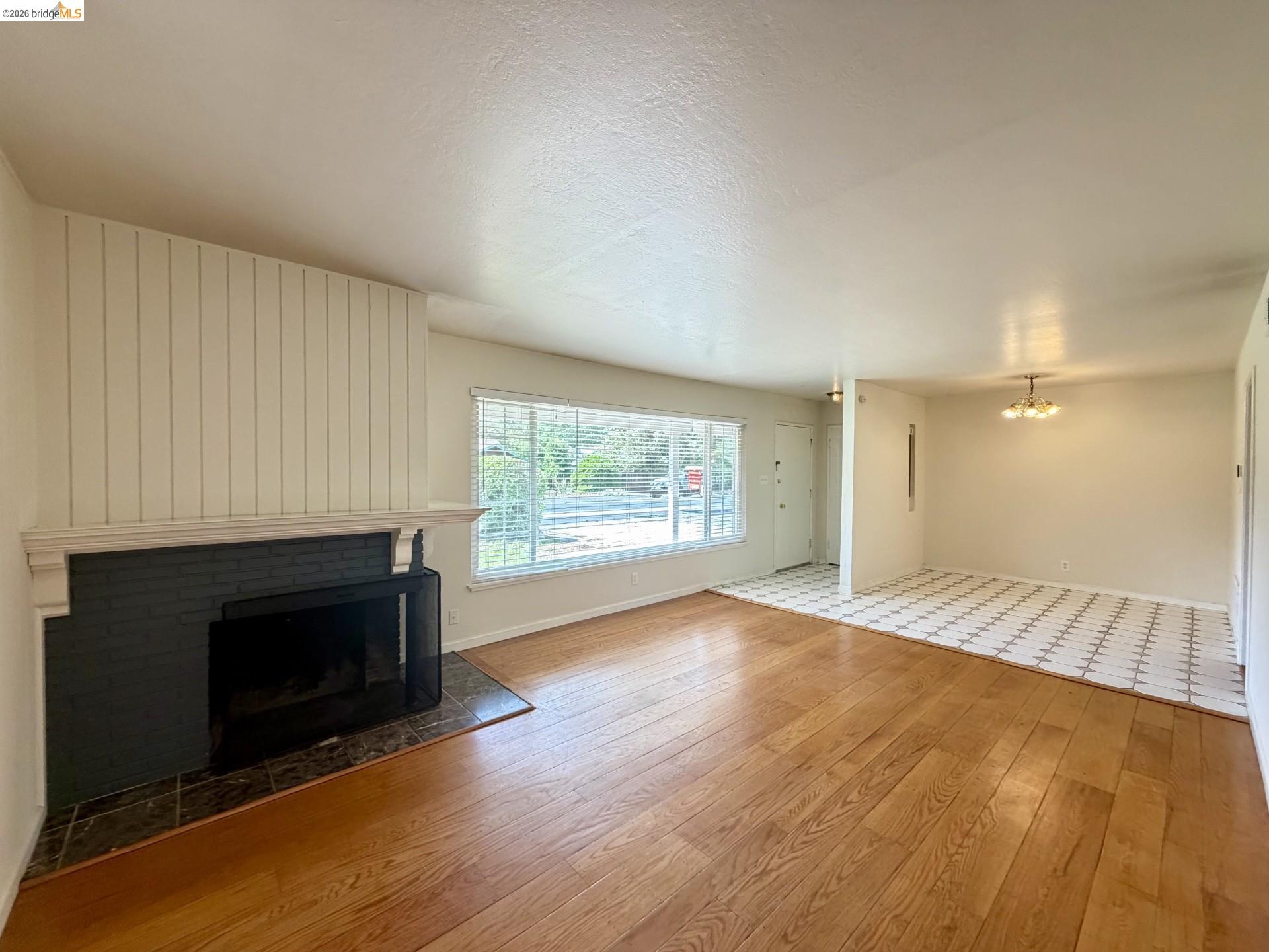 3407 Cowell Road Concord, CA 94518 - Photo 2 of 24 Unfurnished living room featuring light wood-style floors, a brick fireplace, and suspended lighting