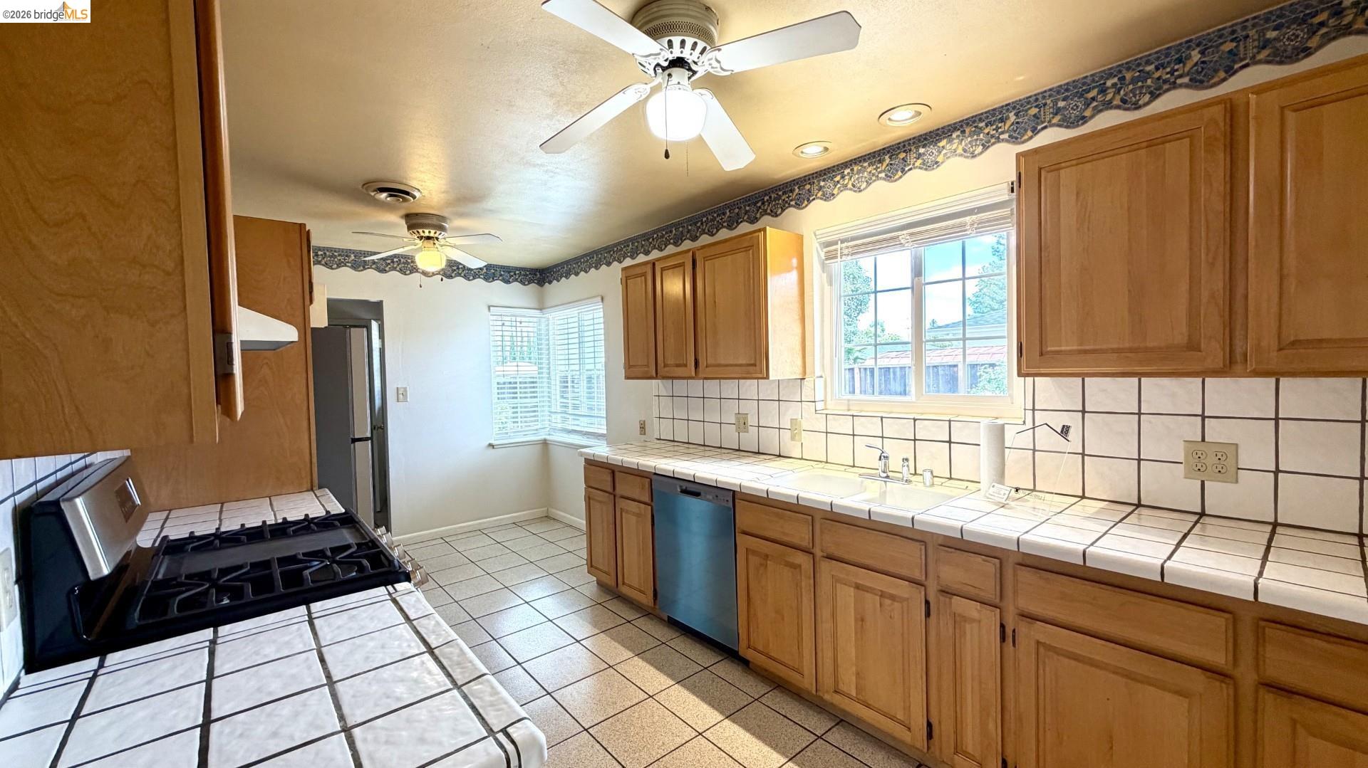 3407 Cowell Road Concord, CA 94518 - Photo 10 of 24 Kitchen featuring tile countertops, tasteful backsplash, stainless steel appliances, light tile patterned floors, and a ceiling fan