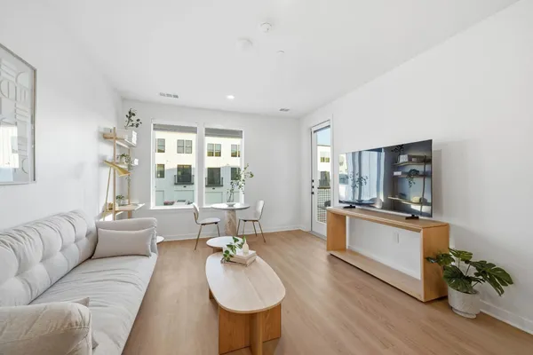a living room with stainless steel appliances granite countertop furniture a couch and a large window