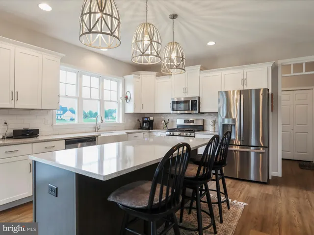 a kitchen with stainless steel appliances granite countertop a sink a stove a refrigerator cabinets a dining table and chairs