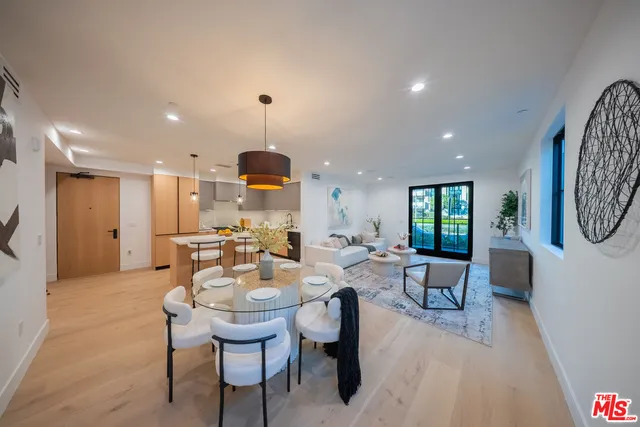 a view of a dining room and livingroom with furniture wooden floor a rug a painting and a chandelier