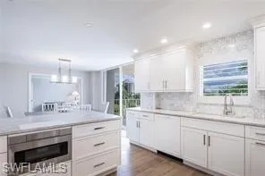 a kitchen with white cabinets and sink
