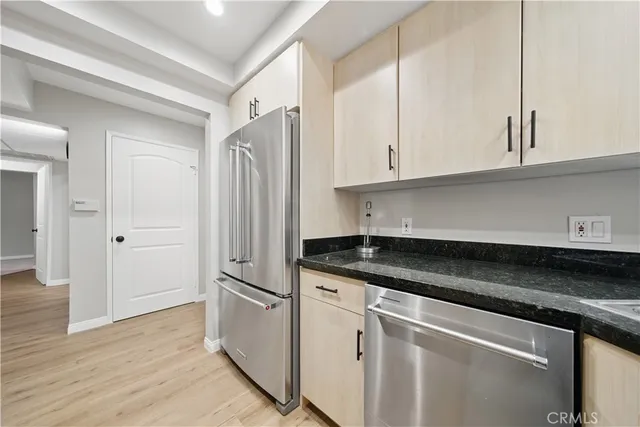 a kitchen with granite countertop a refrigerator sink and cabinets