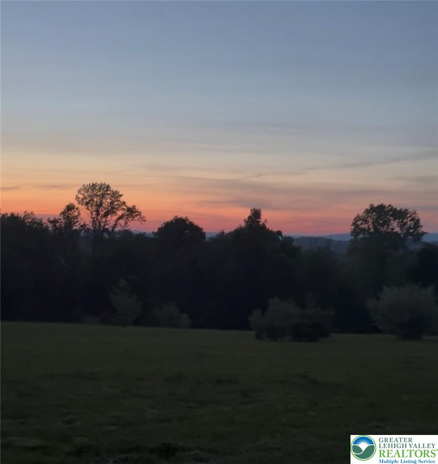 5747 Kernsville Road Orefield, PA 18069 - Photo 56 of 56 A tranquil rural vista unfolds with a pastel twilight painting the sky above the tree line.