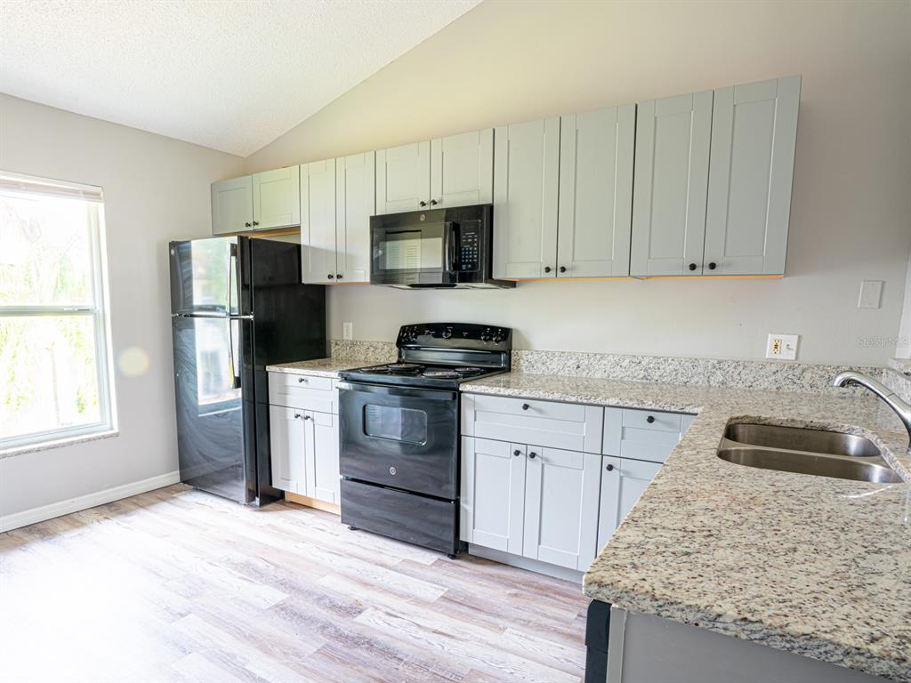 3651 North Goldenrod Road, Unit E205 Winter Park, FL 32792 - Photo 8 of 19 a kitchen with granite countertop a refrigerator stove and sink