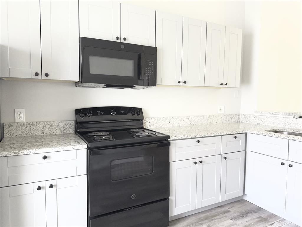 3651 North Goldenrod Road, Unit E205 Winter Park, FL 32792 - Photo 9 of 19 a kitchen with white cabinets and black appliances