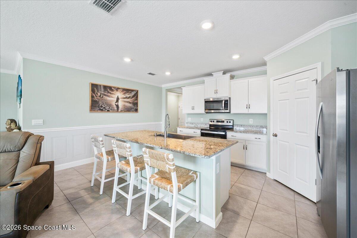 7499 Tourmaline Drive Grant, FL 32949 - Photo 7 of 41 a kitchen with stainless steel appliances granite countertop a stove a sink a microwave a refrigerator and cabinets