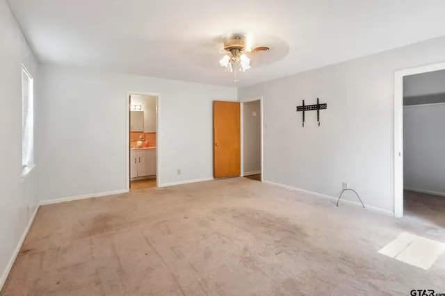 a view of an empty room with a chandelier fan