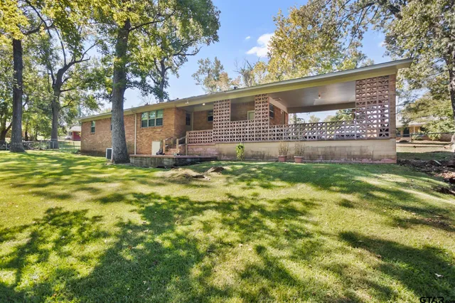 a view of a house with big yard and a large tree