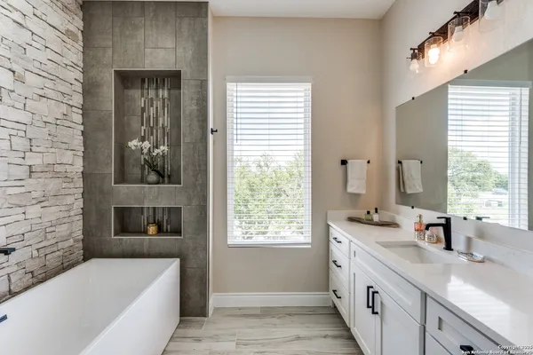 a bathroom with a granite countertop sink and a bathtub
