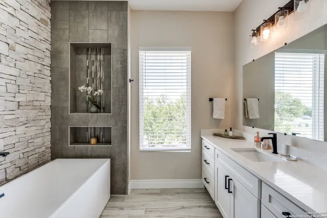 a bathroom with a granite countertop sink and a bathtub
