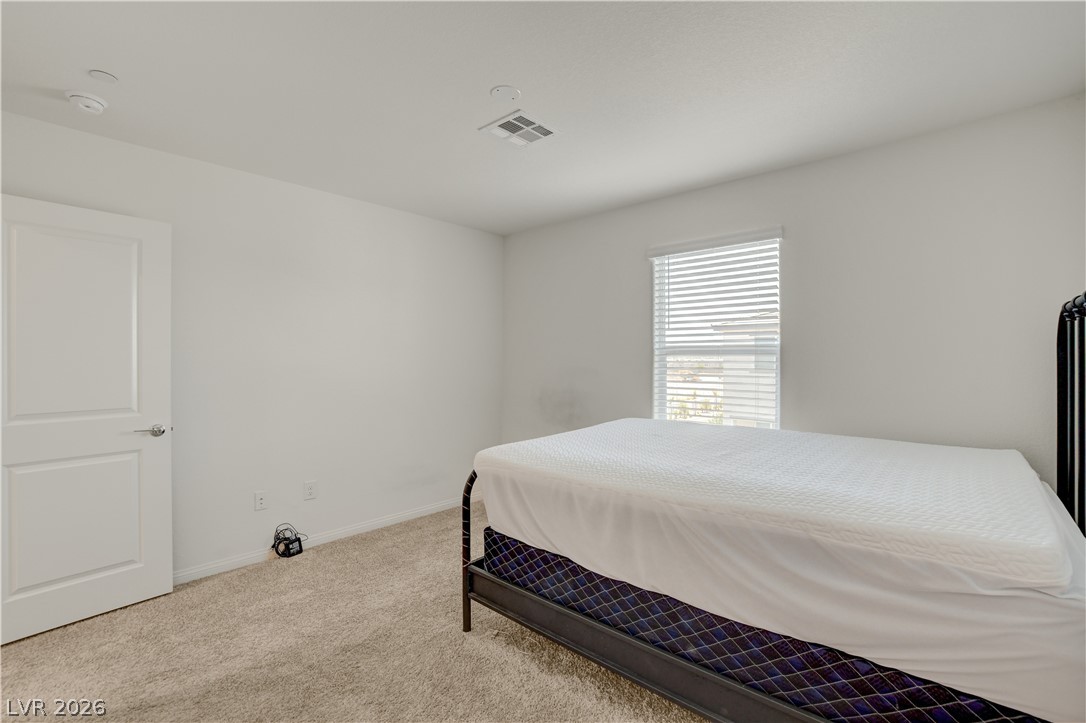 6924 Spicy Merlot Street North Las Vegas, NV 89086 - Photo 31 of 83 A well-lit bedroom provides ample space for comfortable living with neutral tones and carpeted flooring.